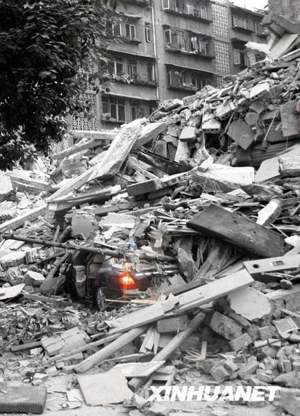 2008年5月12日，成都都江堰市一辆被埋在垮塌废墟里的汽车车灯仍在闪烁（经技术处理）。