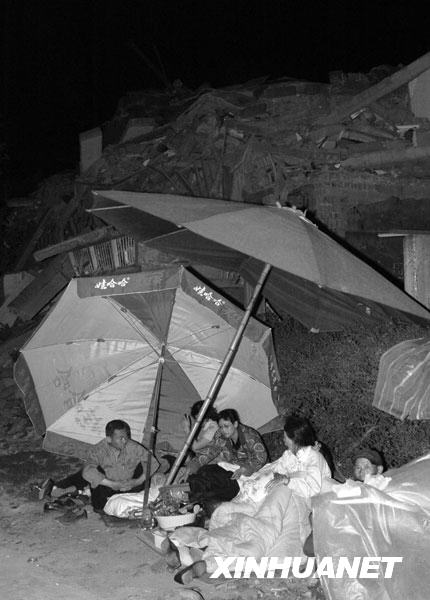 2008年5月13日凌晨，绵竹市汉旺镇的一些居民露宿在垮塌的建筑前。