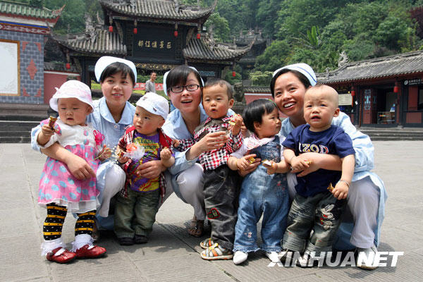 5月11日，三名护士王丽（左二）、罗云莉（左四）和张兰（右二）在曾经护理过“地震宝宝”的广场上与5名婴儿合影。