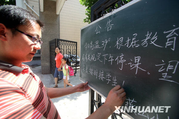 6月24日，一名郑州市民在街头用报纸遮挡烈日。