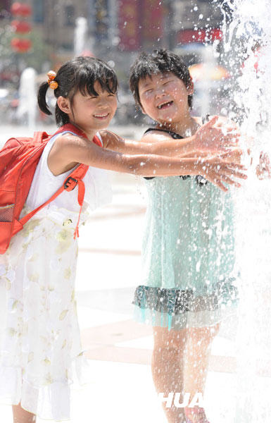 6月24日，孩子们在郑州市二七广场的喷泉旁消暑。